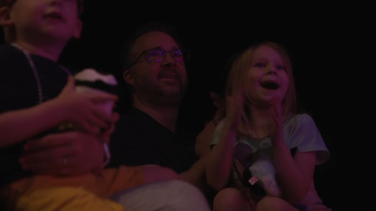 A father and two children laughing in the audience